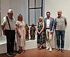 Drei Männer und zwei Frauen mit zwei Holzskupturen im Museum